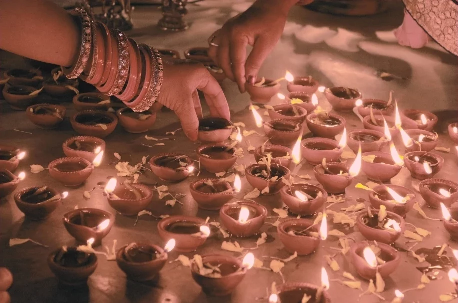 Mains ornées de bracelets allumant des bougies indiennes traditionnelles lors d'un pèlerinage en Inde