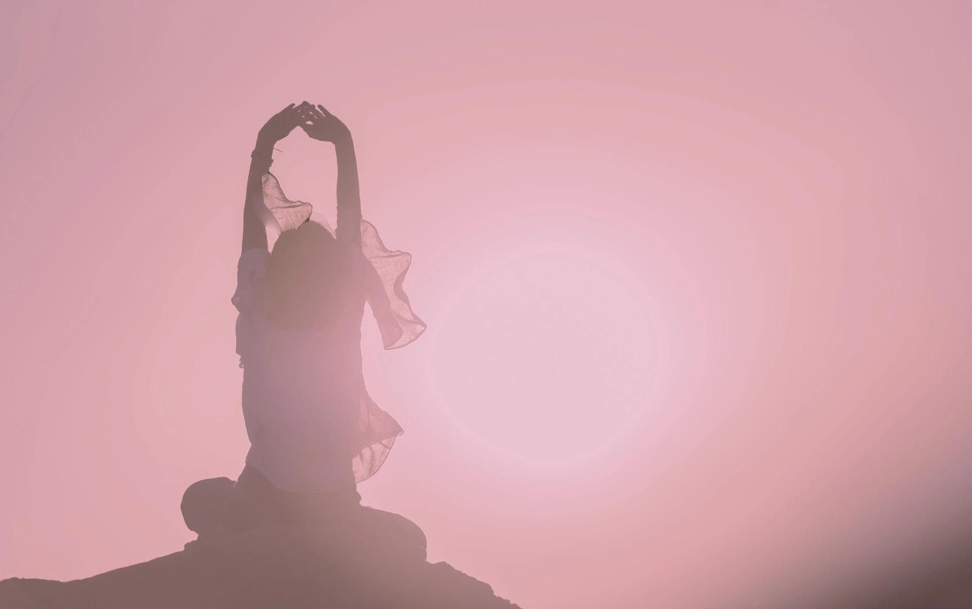 Silhouette de femme en posture de yogathérapie au lever du soleil, bras levés vers le ciel à Lorgues, Var.