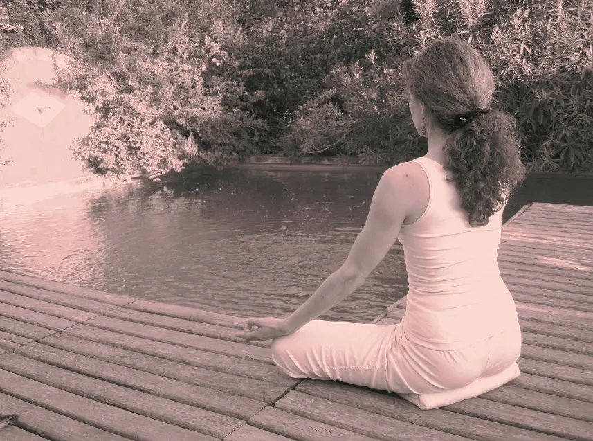 Femme en méditation sur un ponton en bois au bord de l'eau, sophrologie en pleine nature dans le Var
