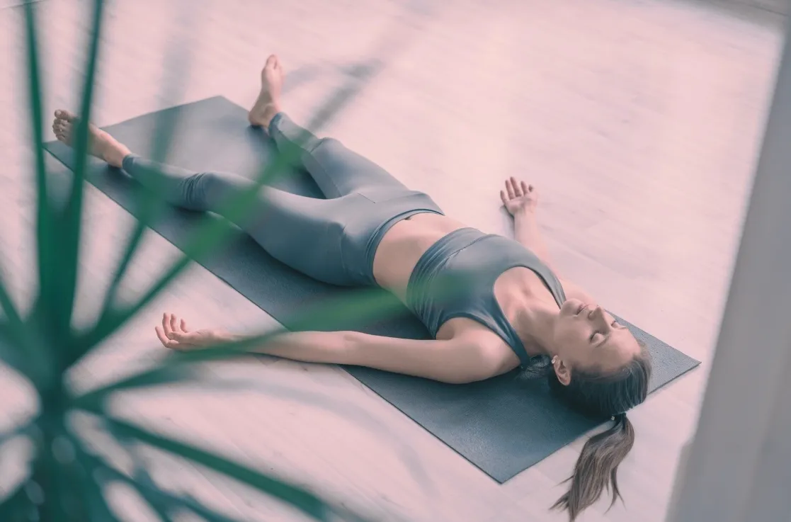 Femme allongée en posture de relaxation Savasana sur un tapis lors d'une séance de sophrologie à Lorgues dans le Var.