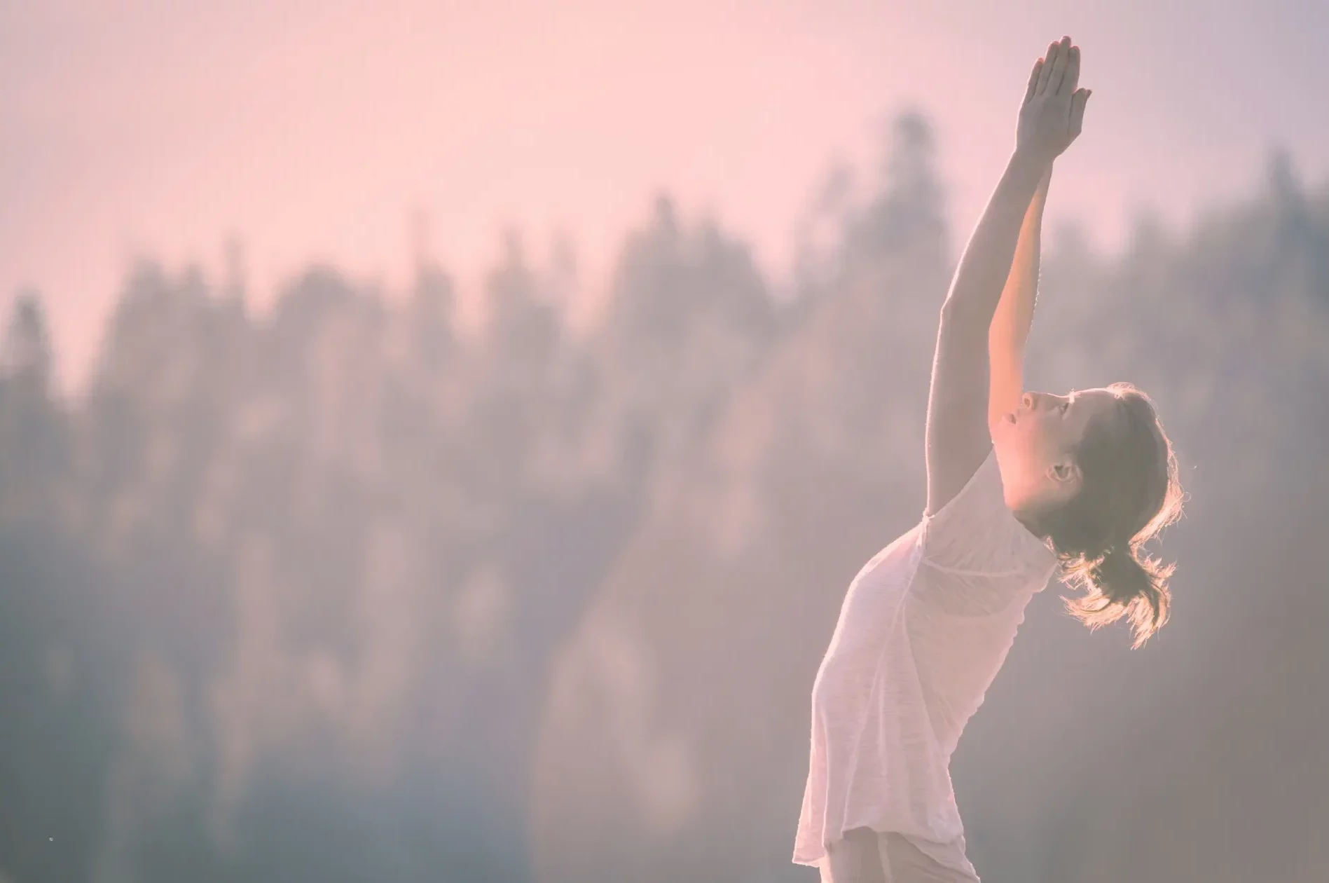 Femme pratiquant une posture de yoga et sophrologie en plein air face au soleil, lors d'une séance près de Lorgues, Var.