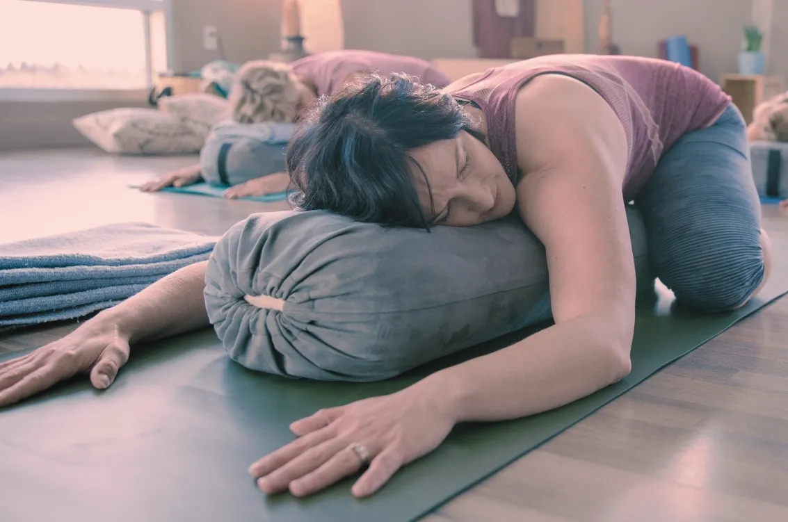 Femme en posture de relaxation sur un traversin lors d'un cours de yogathérapie et yin yoga près de Flayosc dans le Var.