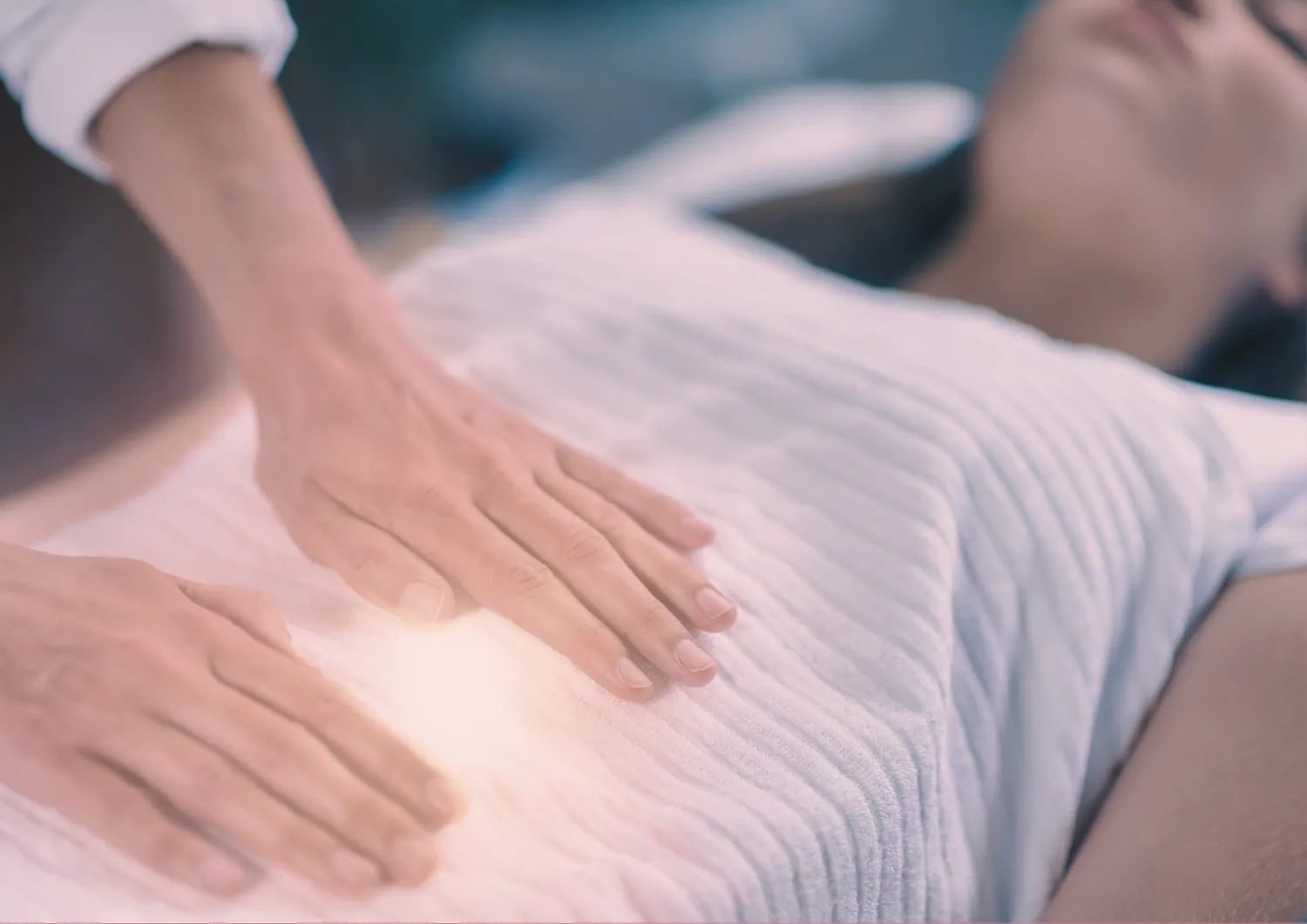Mains d'une praticienne posées doucement sur l'abdomen d'une femme lors d'un soin énergétique près de Vidauban, Var.