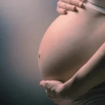 Gros plan sur le ventre rond d'une femme enceinte accompagnée en sophrologie prénatale près de Draguignan.